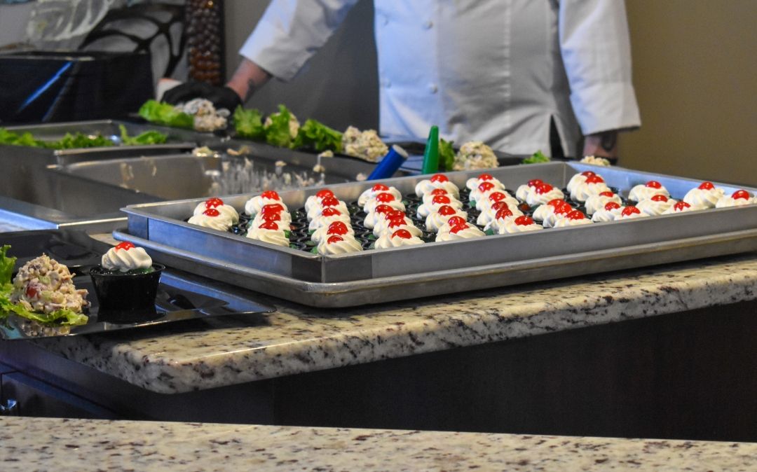 A chef plates fresh caprese skewers at a Willow Brook Village courtyard event, showcasing the quality dining offered to residents in Delaware, Ohio.
